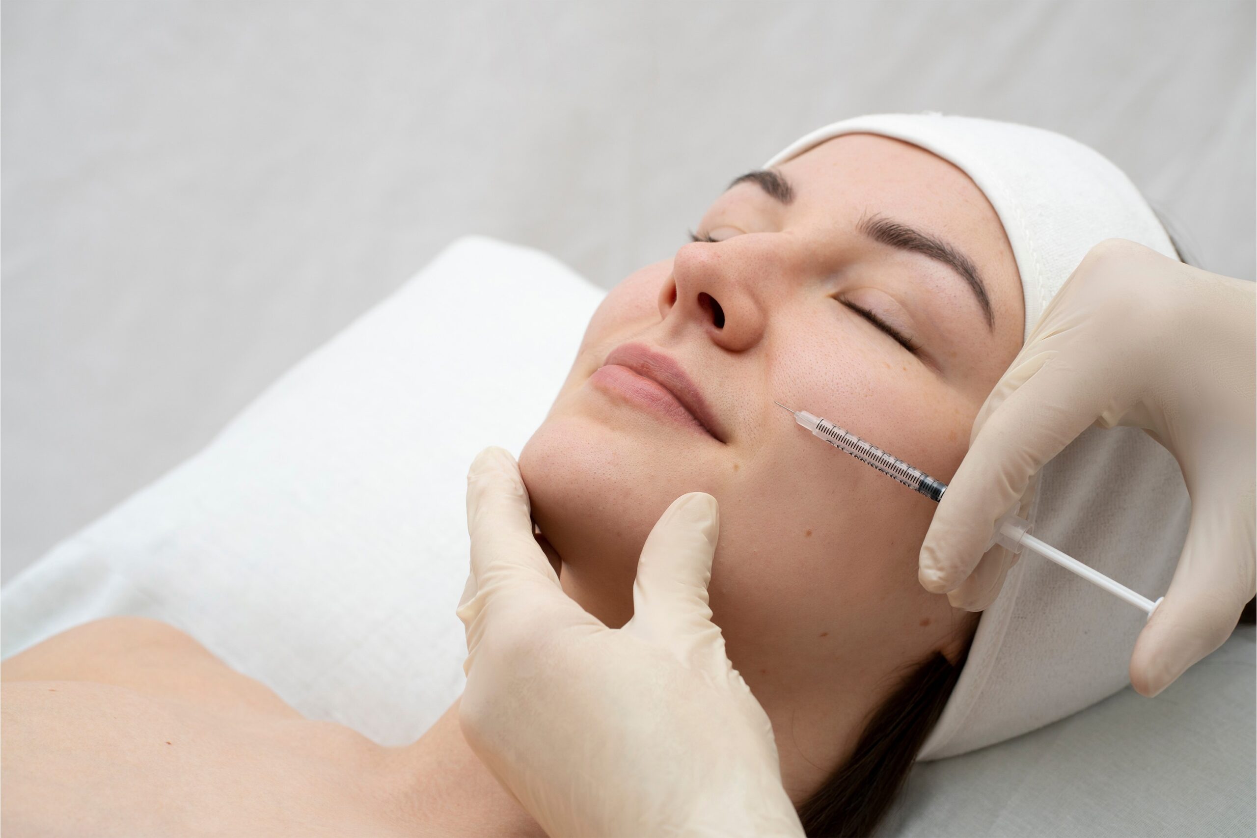 close-up-relaxed-brunette-woman-with-soft-skin-posing-camera-with-closed-eyes-isolated-white 1 Dermal Fillers vs. Anti-Wrinkle Injections in London: Which Is Right for You?